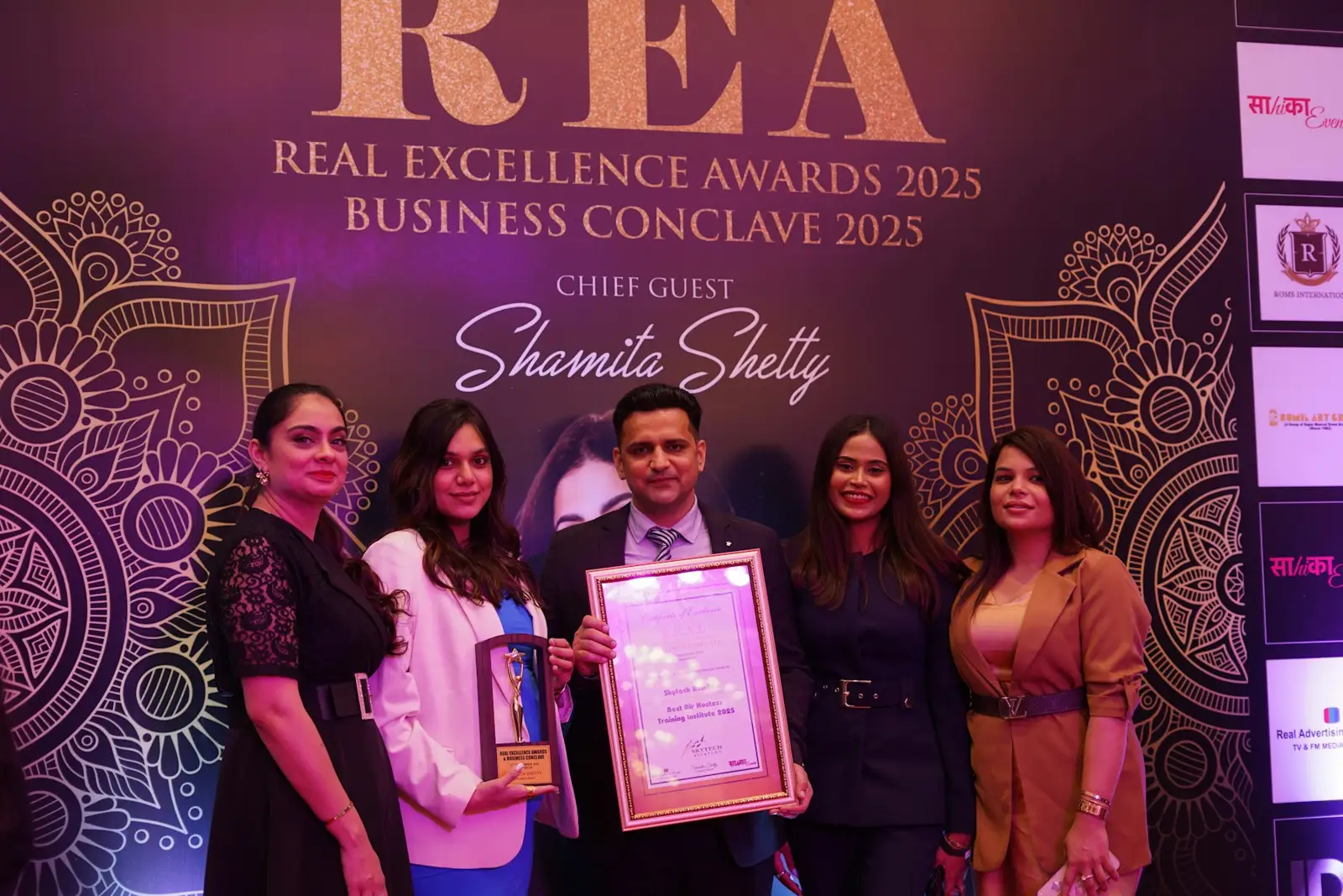 Group poses with award at real excellence awards 2025