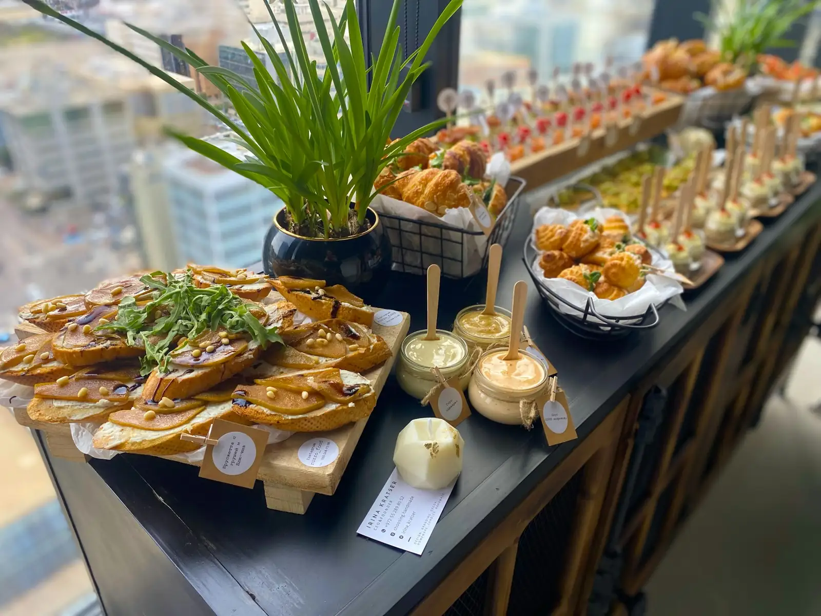 Catering spread with pear bruschetta, pastries, and small jars of dip on a table