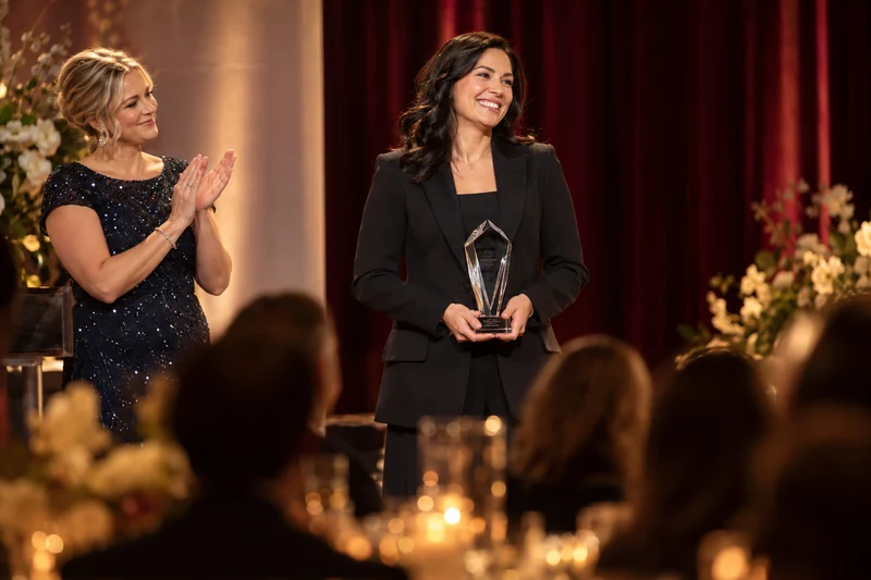 Award recipient holding a crystal trophy as a presenter applauds