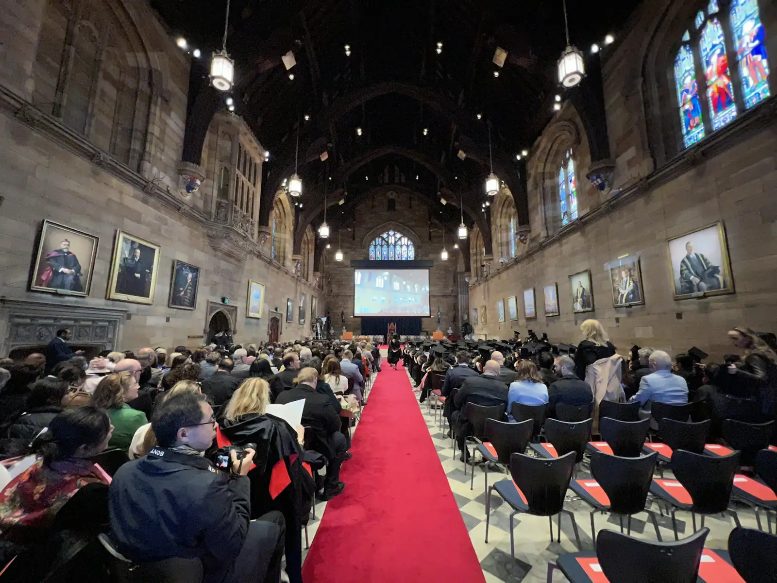 a group of people sitting in a room with a large screen