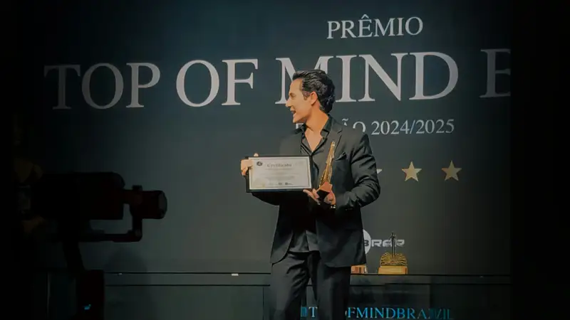 Award recipient holding a trophy in front of a branded ceremony backdrop