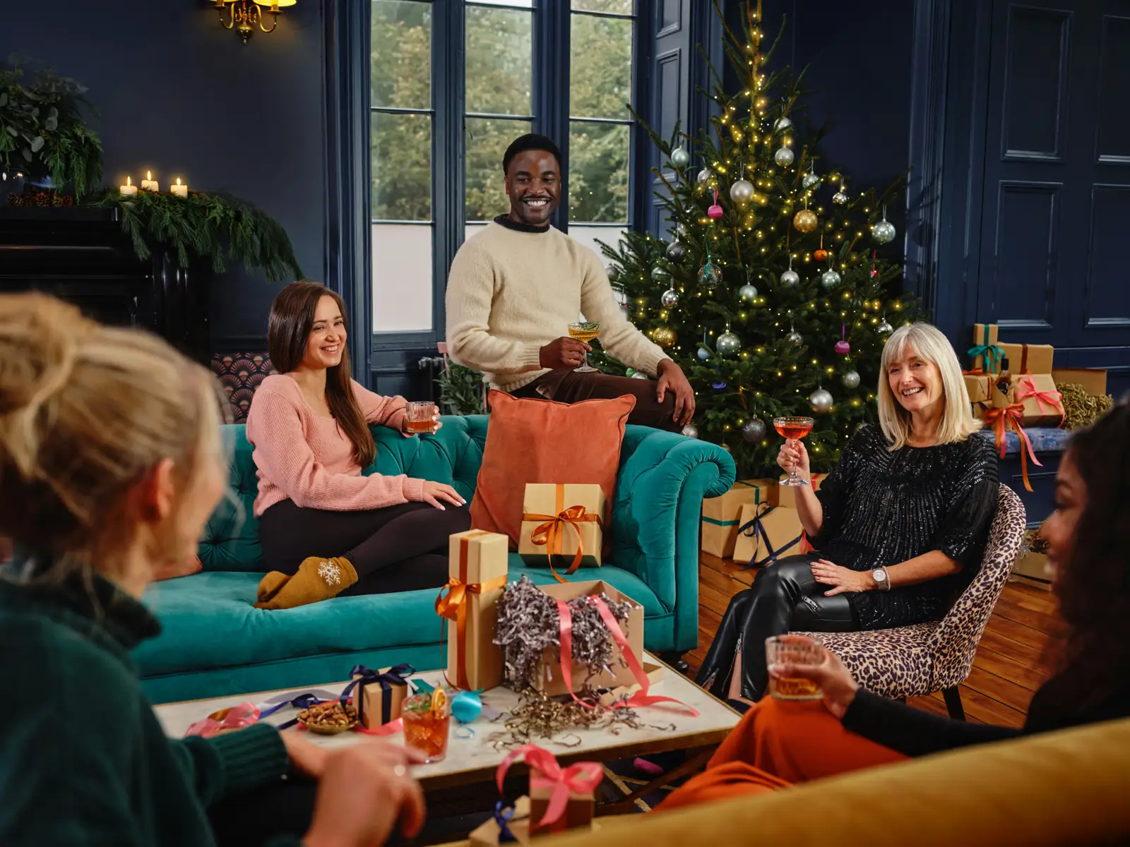 Colleagues and friends gathered beside a Christmas tree for a holiday celebration