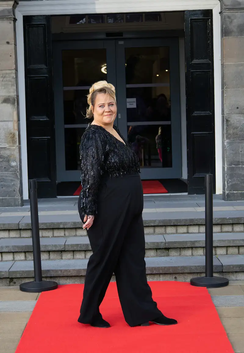 Guest posing on a red carpet outside an event entrance