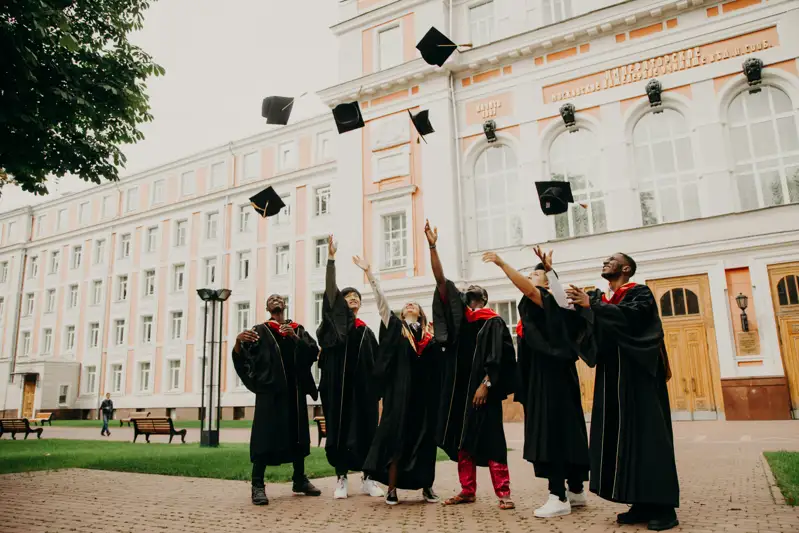University graduates throwing caps outside a campus building